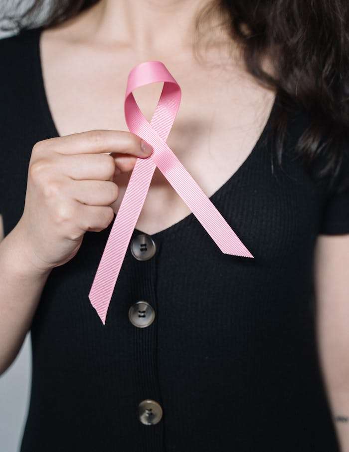 woman-holding-pink-ribbon-5483003 A woman holds a pink ribbon symbolizing breast cancer awareness, promoting health advocacy.